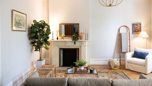 A living room with a fireplace, a sofa, a coffee table, and a chandelier. - Charming Apt. with Marble Mantel (Troy)