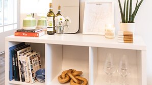 A well-organized shelf with books, wine bottles, a mirror, a framed map, and a potted plant. - Peaceful, Artsy North Troy Riverview Apt (Troy)