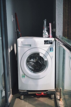 A front-loading washing machine on a cart in a narrow space, possibly a laundry room or utility area. - Dalat Center Residence (Dalat)