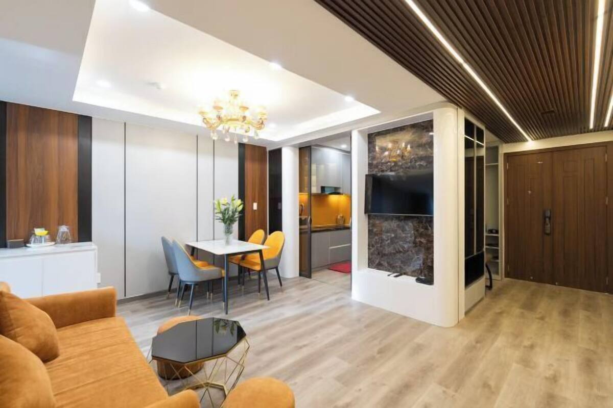A modern living room with a dining area, a kitchen, and a separate bathroom.