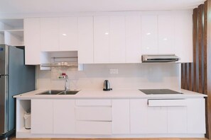 A modern kitchen with white cabinetry, a stainless steel sink, and a built-in oven. - Dalat Center Residence (Dalat)