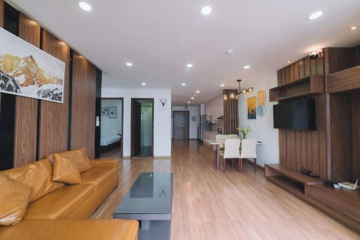 A modern living room with a leather sofa, a coffee table, and a flat-screen TV mounted on the wall.