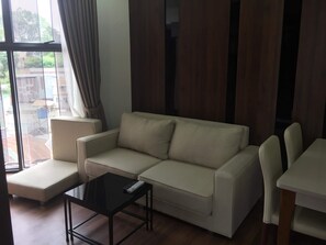 A living room with a sofa, a coffee table, and a dining table with chairs. - Dalat Center Residence (Dalat)
