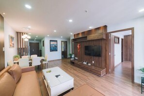 A modern living room with a sofa, coffee table, TV, and dining area. - Dalat Center Residence (Dalat)