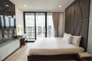 Una habitación de hotel moderna con una cama grande, un televisor en la pared y vistas a la ciudad a través de la ventana.