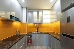 A modern kitchen with a built-in oven, a stainless steel refrigerator, and a sink with a faucet. - Dalat Center Residence (Dalat)