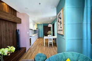 Un interior moderno con comedor, cocina y un sofá color turquesa.