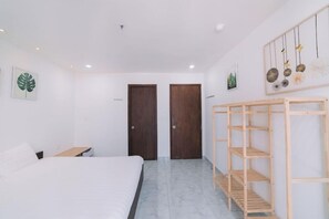 A bedroom with a bed, two doors, a wooden shelf unit, and artwork on the walls. - Dalat Center Residence (Dalat)
