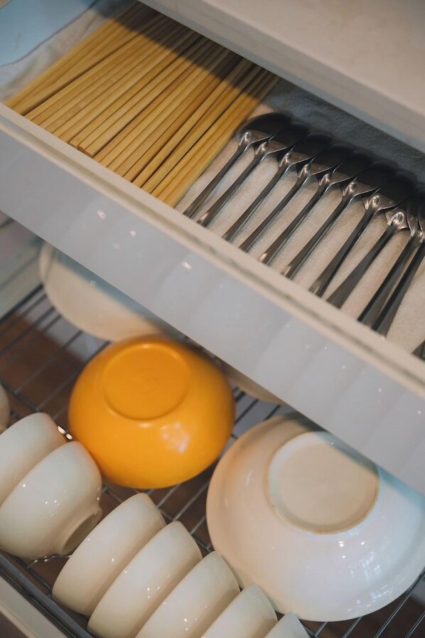 Une cuisine avec un plan de travail blanc, une casserole jaune et plusieurs assiettes blanches.