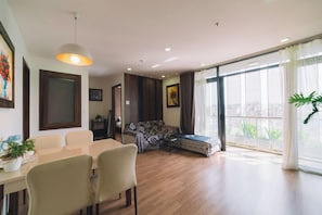 A modern living room with a dining area, large windows, and a sofa. - Dalat Center Residence (Dalat)