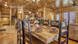 L’intérieur d’une cabane en bois comprend un coin repas, une cuisine et un escalier menant à un étage supérieur.