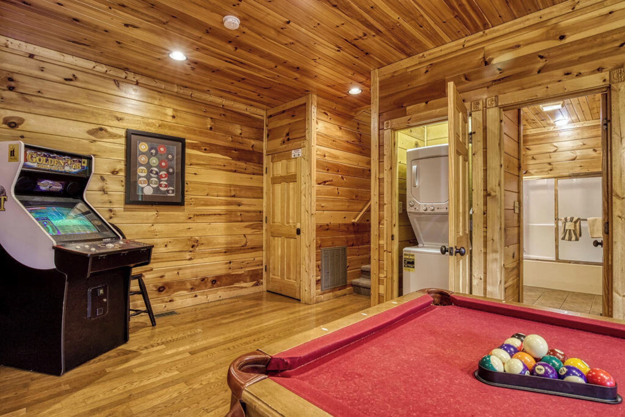 A wooden interior with a pool table, a pool cue, and a pool table ball rack.