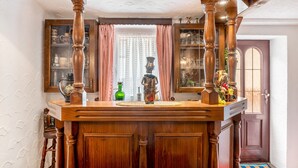 Een houten bar met een decoratief beeld, een glazen kast en een deur met een raam.