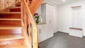 Een houten trap die leidt naar een kamer met witte kasten en een bank.