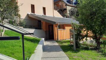 Un edificio residencial con fachada de piedra, exterior de madera y una pequeña estructura de madera con techo metálico.