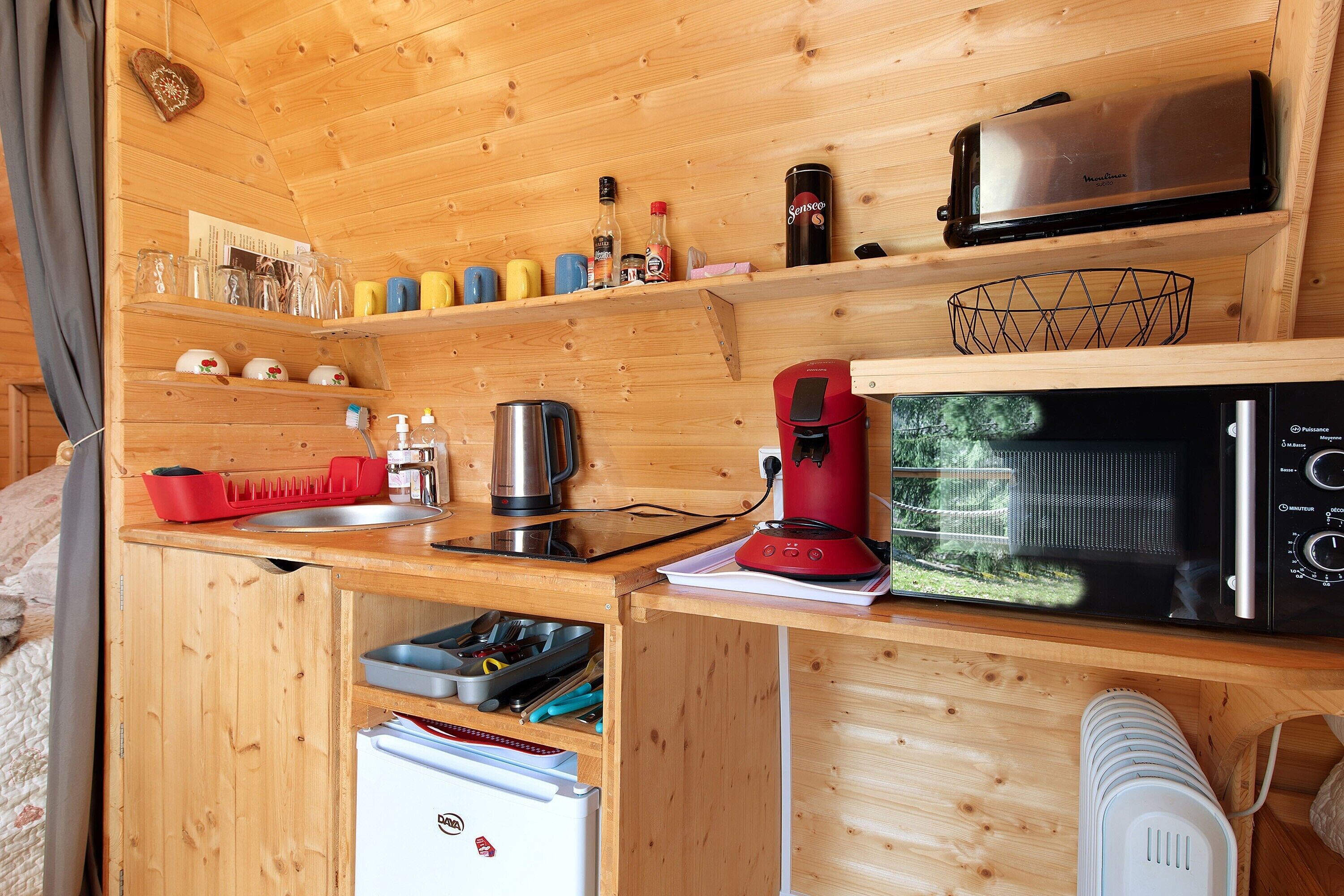 A compact kitchen with a microwave, coffee maker, and various kitchen utensils.