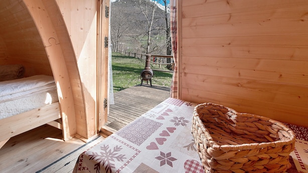 Une cabane en bois avec un lit, un panier en osier et une vue sur une montagne.