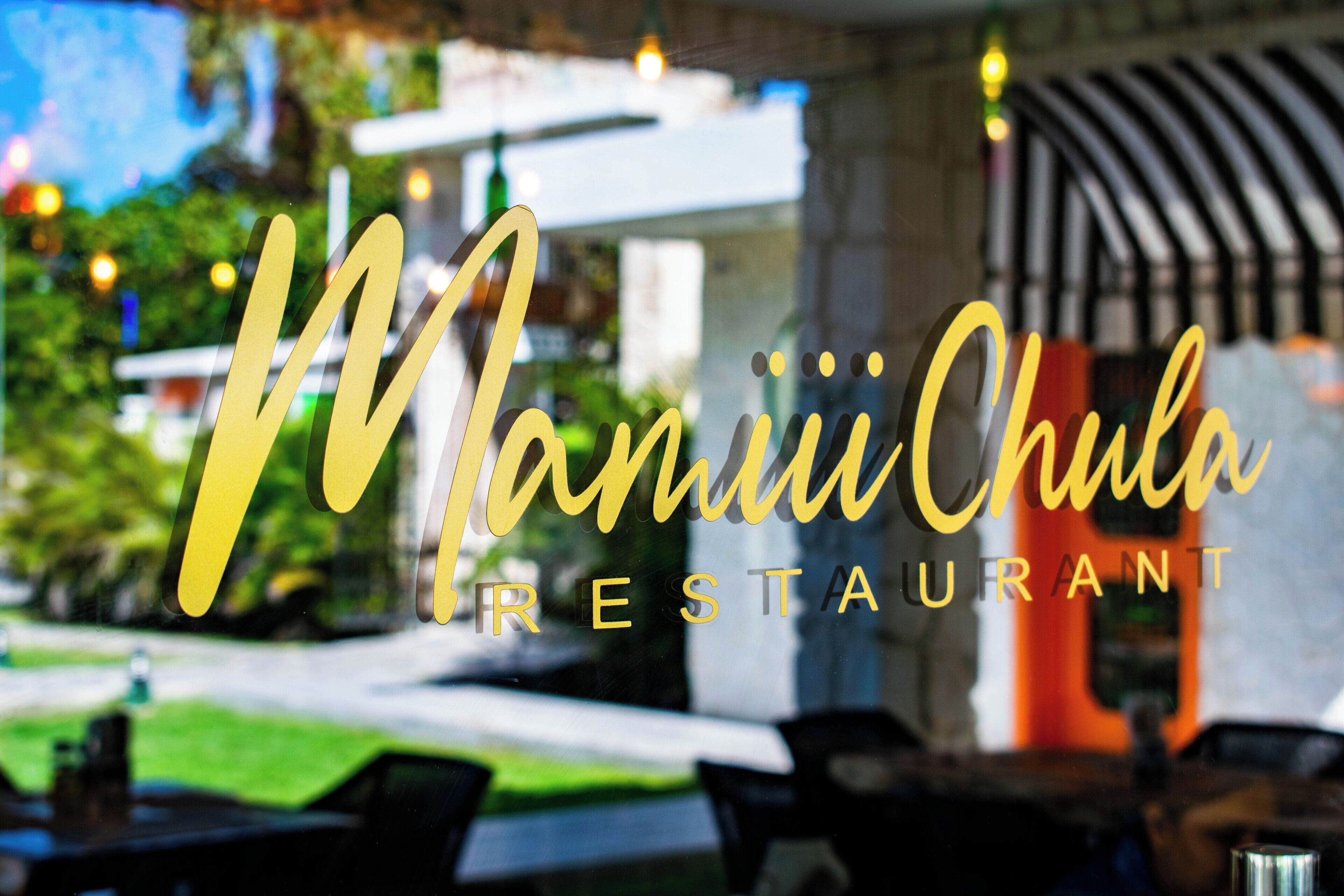 Un letrero de restaurante con el nombre 'Manii Chula Restaurant' en letras cursivas y mayúsculas.