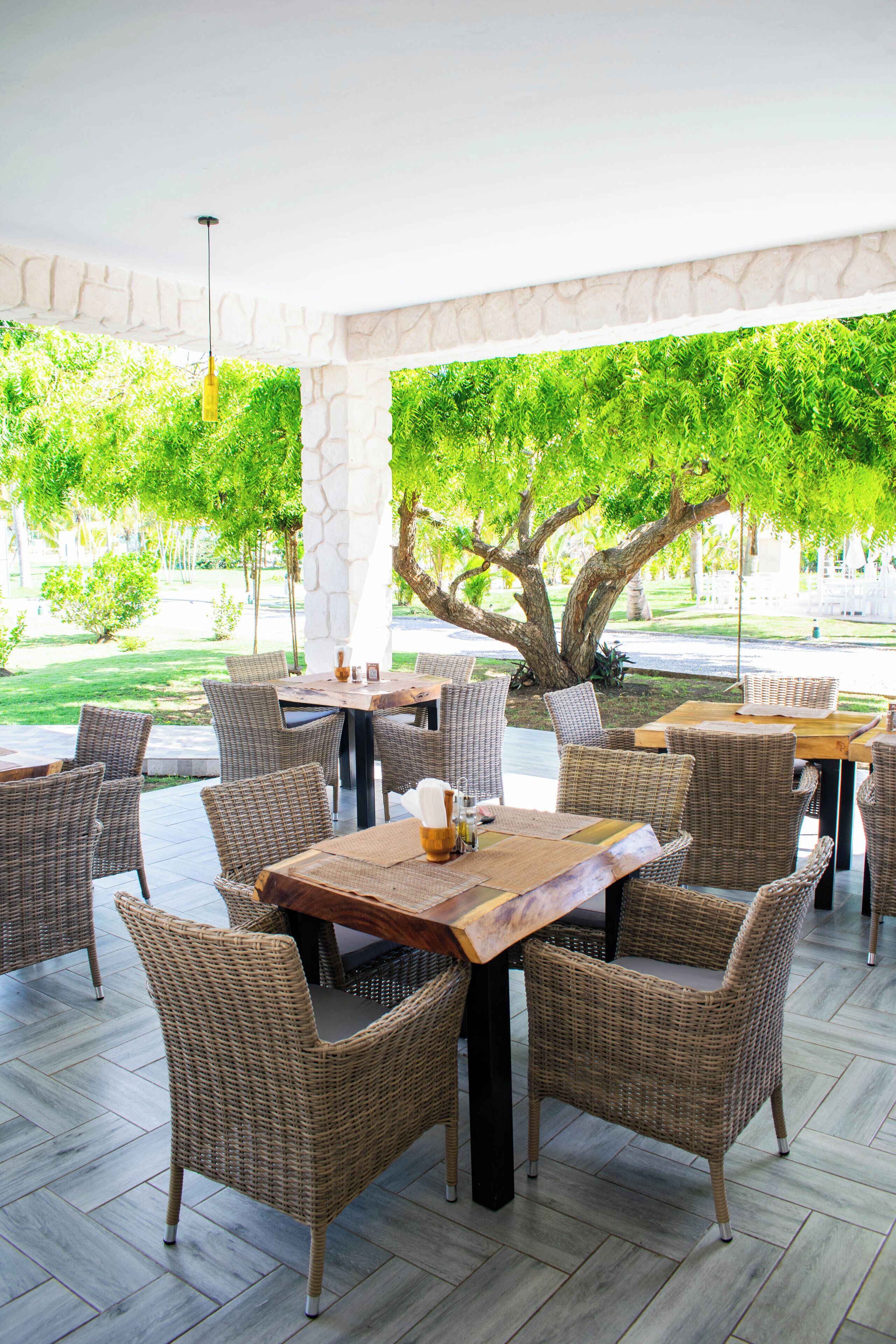 Un patio al aire libre con mobiliario de mimbre y un pilar de piedra.