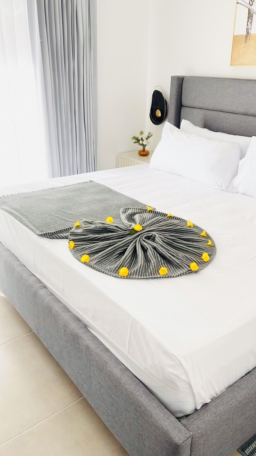 Un lit bien fait, recouvert d’une couverture rayée grise et blanche, avec un oreiller gris et un oreiller blanc.