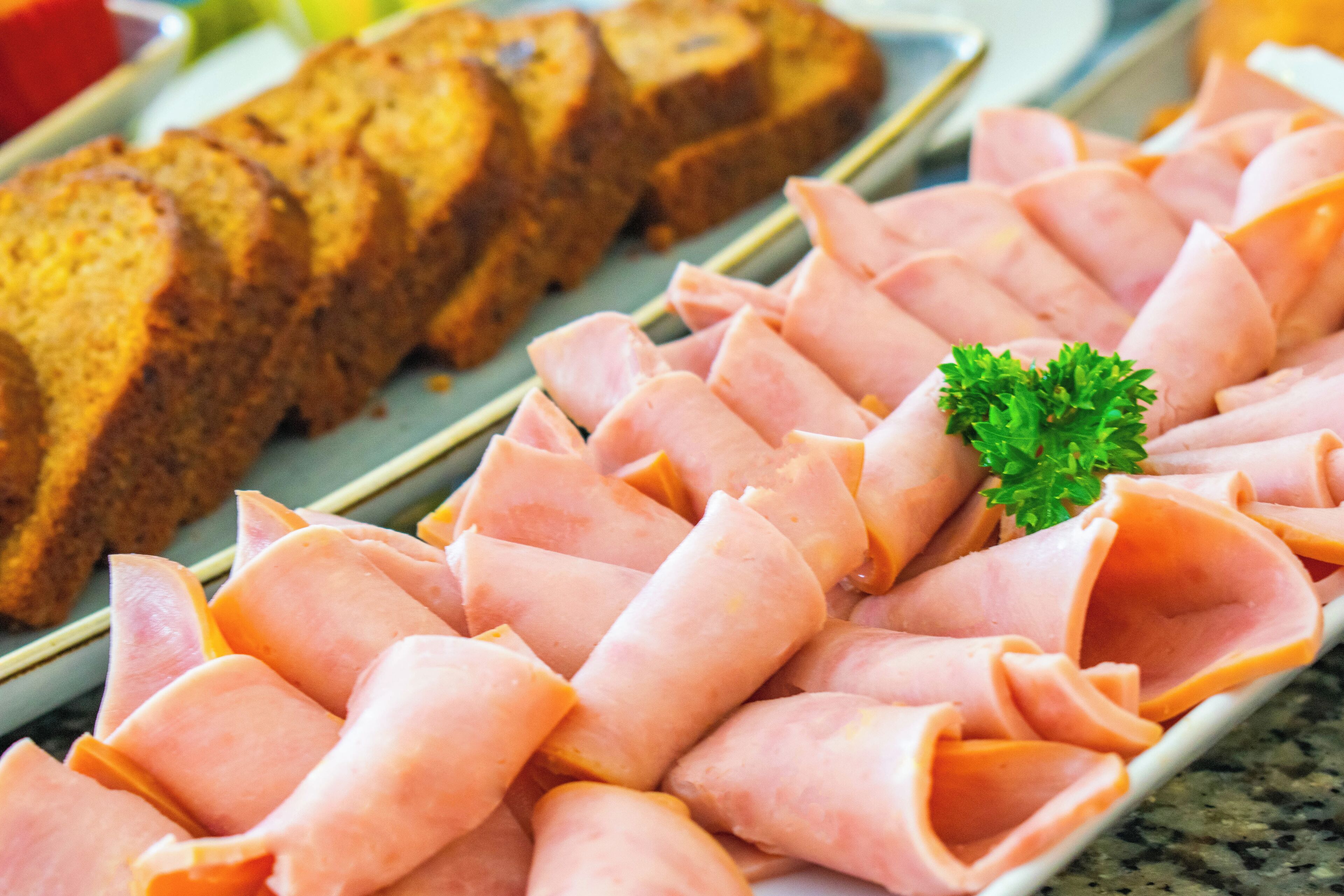A plate of sliced ham and bread.