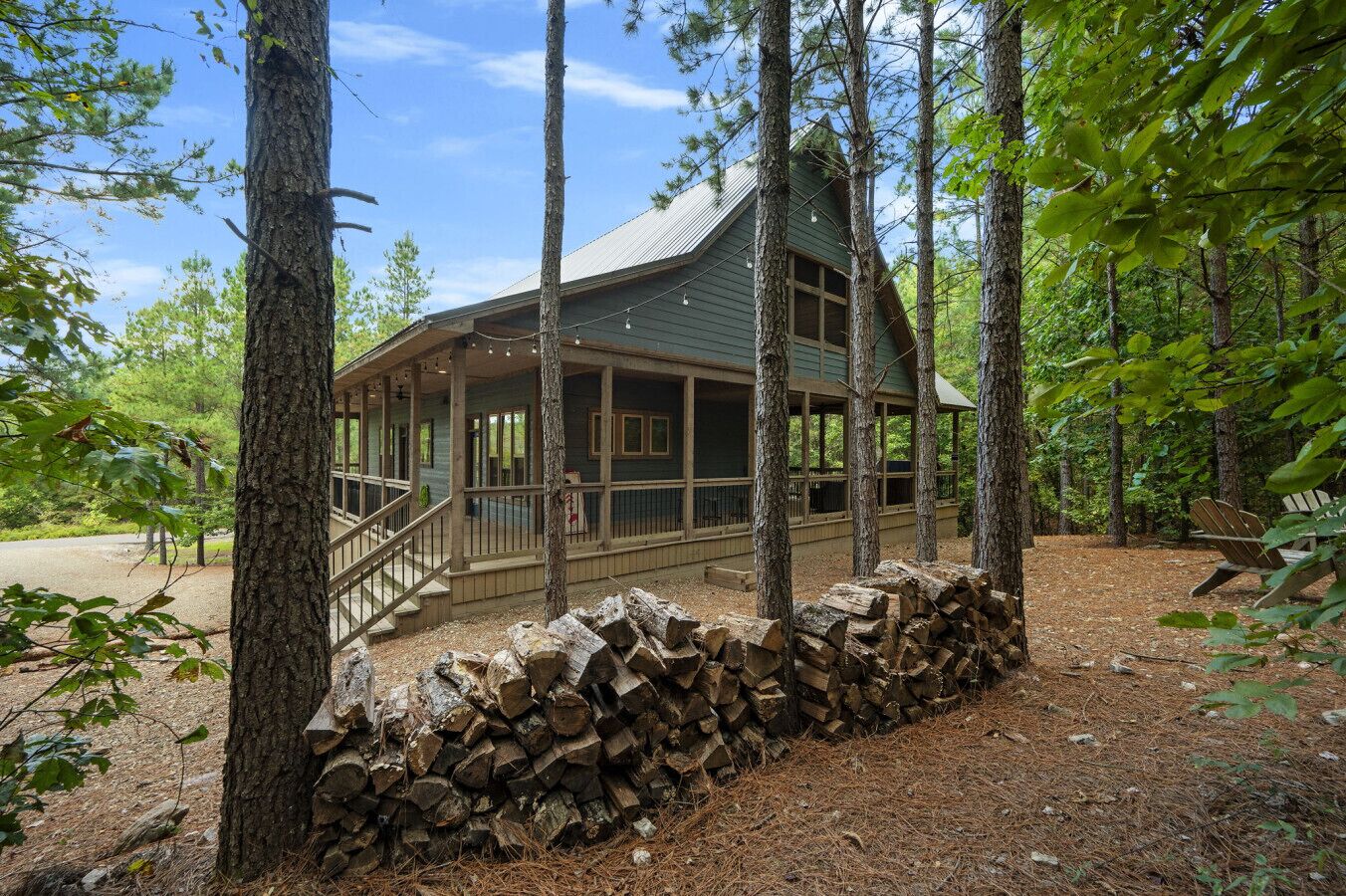 Eine Hütte mit Veranda, umgeben von Bäumen und einem Holzstapel.