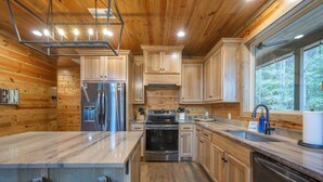 A modern kitchen with wooden cabinets, stainless steel appliances, and a large island with seating.