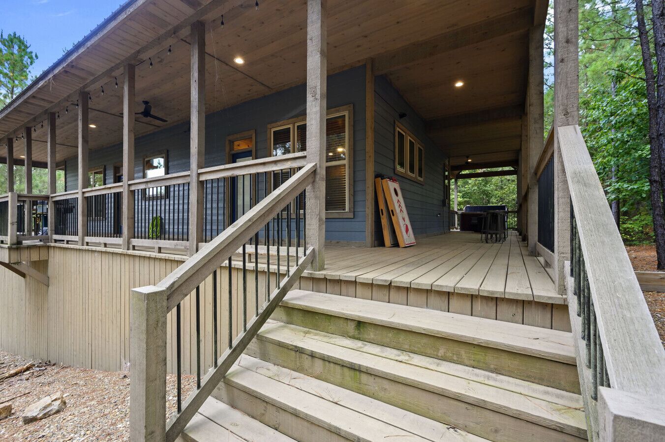 A wooden deck with a staircase leading to a covered porch area.