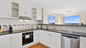 Een moderne keuken met witte kasten, een RVS vaatwasser en een inbouwoven.