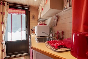 A kitchen with a sink, a microwave, and a red dish rack.