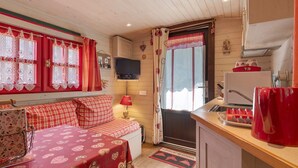 Une pièce confortable avec un lit, une télévision, un petit coin cuisine et une fenêtre avec des rideaux.