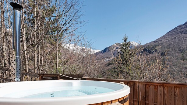Un bain à remous sur une terrasse en bois, avec vue sur les montagnes.