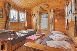 A wooden cabin interior with two beds, a table, and a window. - Roulotte Edelweiss – Unique Wooden Caravan Stay in Gavarnie (Gavarnie-Gèdre)