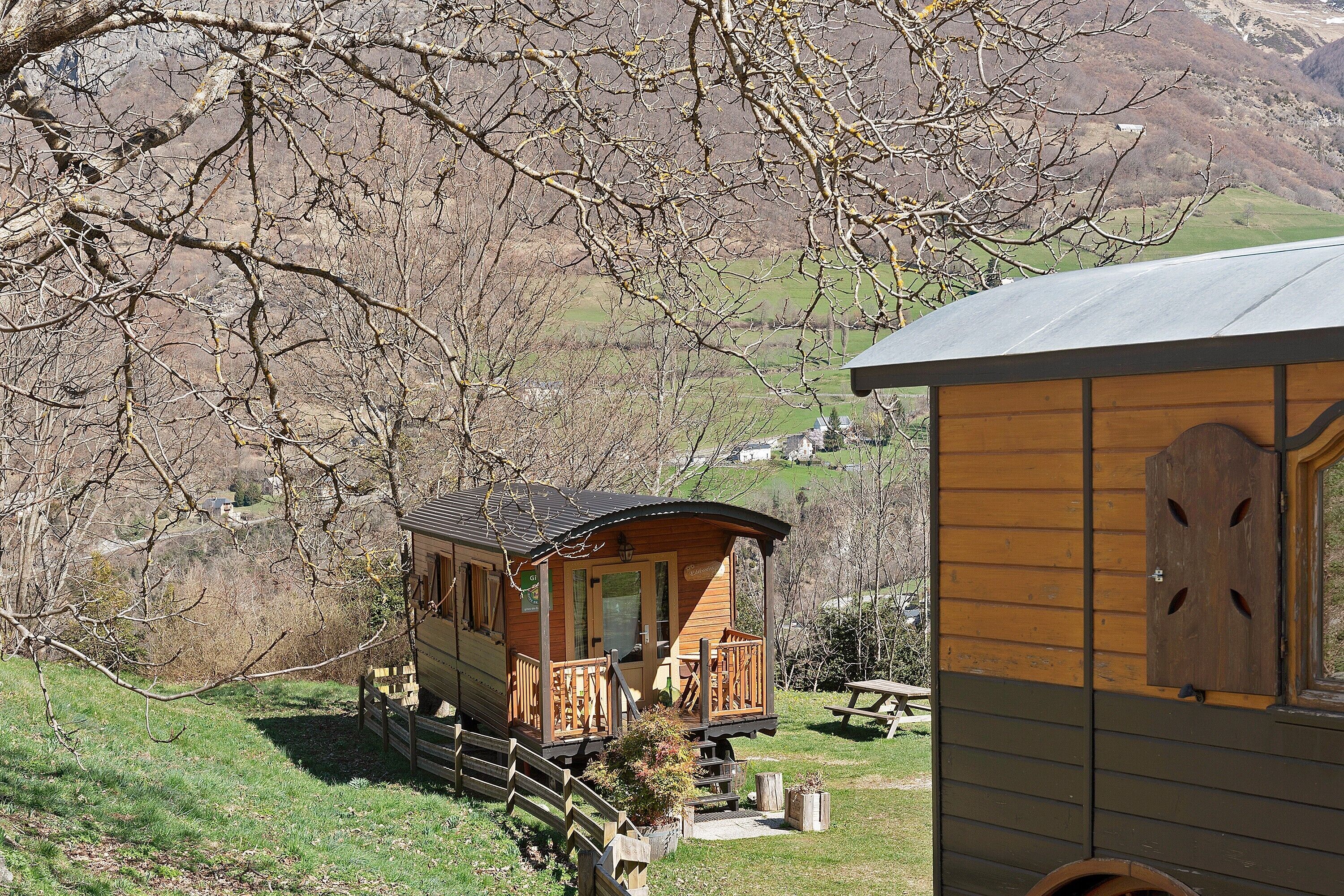 Una cabaña de madera con balcón, un porche pequeño y vistas del paisaje circundante.