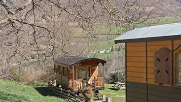 Una cabaña de madera con balcón, un porche pequeño y vistas del paisaje circundante.
