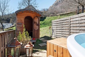 A wooden structure with an arched entrance, a hot tub, and a wooden fence. - Roulotte Edelweiss – Unique Wooden Caravan Stay in Gavarnie (Gavarnie-Gèdre)