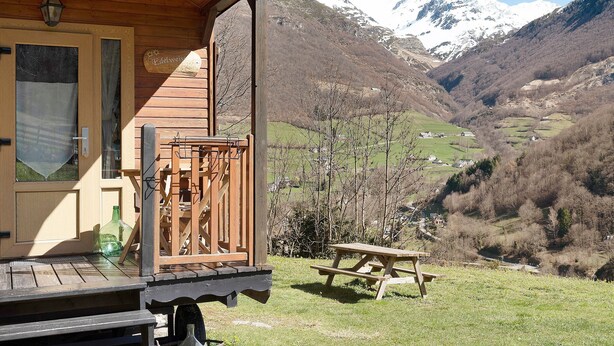 Una cabaña de madera con balcón que da a un valle y montañas.