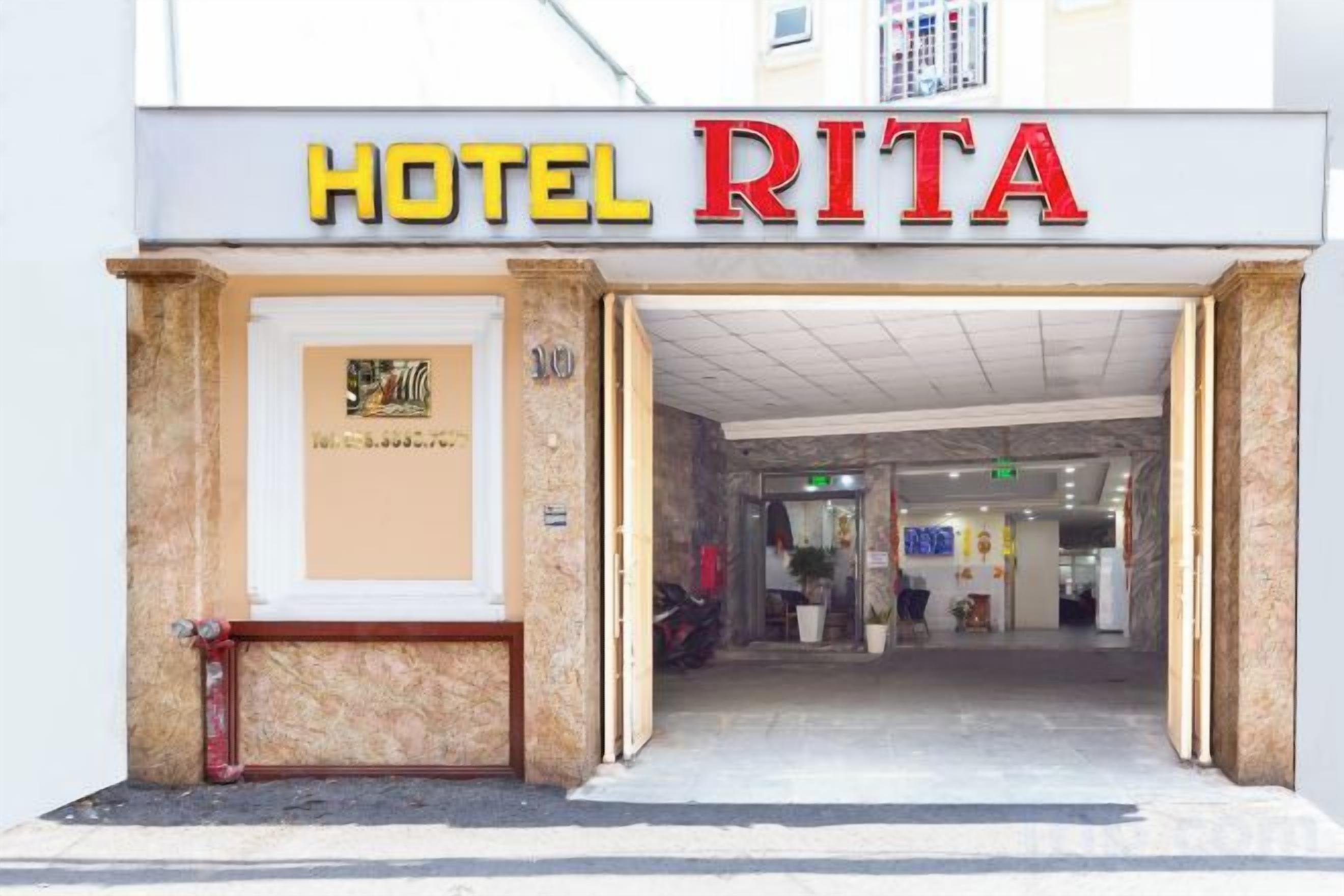 Ingången till ett hotell som heter ”HOTEL RITA”, med en synlig reception och en dörr som är märkt med nummer 100.