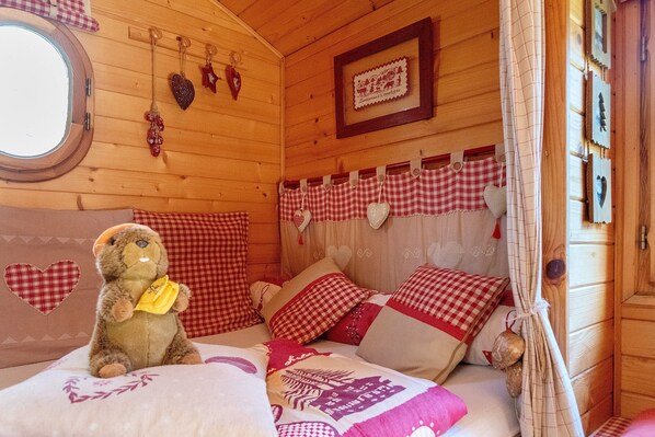 Une chambre confortable dans un chalet en bois, avec un lit, un ours en peluche et des décorations en forme de cœur.