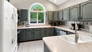 A modern kitchen with grey cabinets, a white refrigerator, and a large window with a view of greenery. - Sugar Hollow in Chittenden (Rutland)