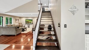 A spacious living area with a wooden floor, a staircase, and a kitchen in the background. - Sugar Hollow in Chittenden (Rutland)