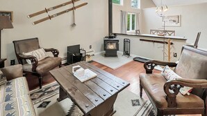 A cozy living room with a fireplace, wooden furniture, and a view of the outdoors. - Sugar Hollow in Chittenden (Rutland)