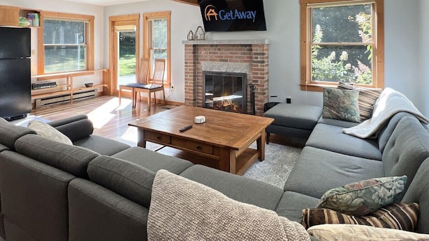 A cozy living room with a fireplace, a large sofa, a wooden coffee table, and a flat-screen TV mounted on the wall. - Hidden Kingdom in Plymouth (Plymouth)