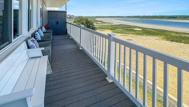 A covered porch with white railings, a bench, and a row of wicker chairs with cushions. - Admiral s Quarters in Wells (Wells)