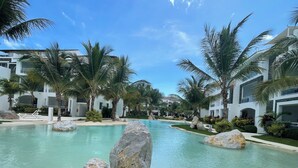 Ein Resort-Pool mit klarem Wasser, umgeben von Palmen und modernen Gebäuden.