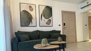Ein Wohnzimmer mit einem grünen Sofa, zwei Beistelltischen und abstrakter Wandkunst.