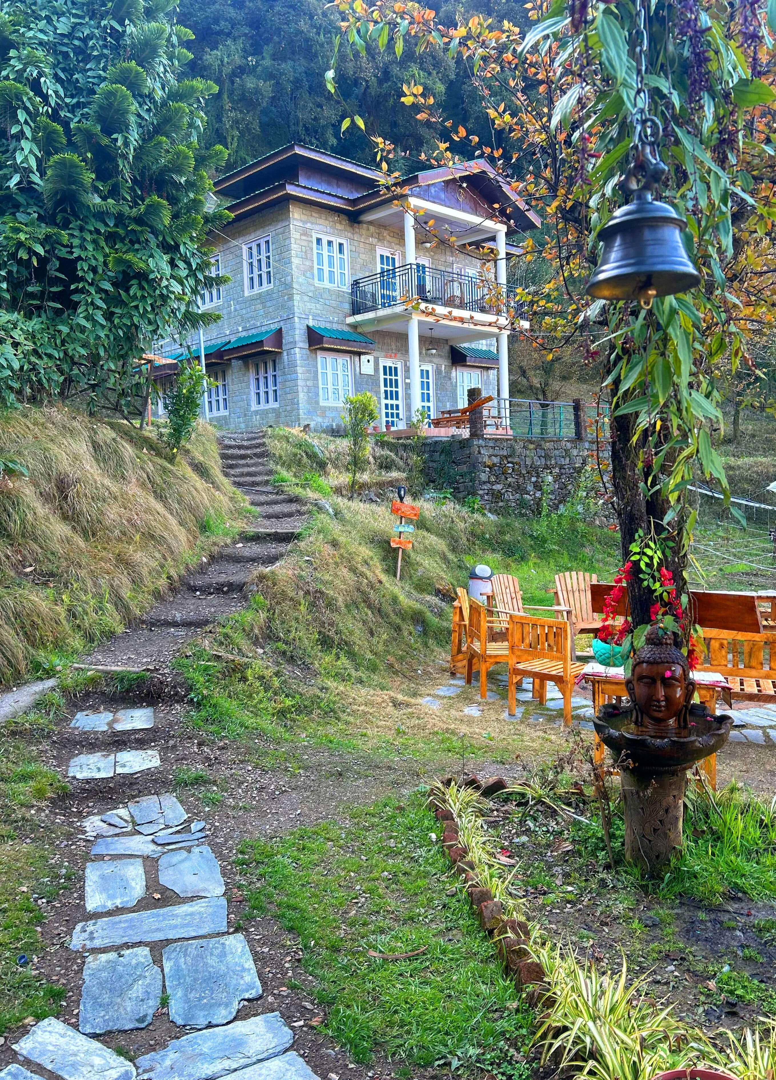 A stone pathway leading to a stone building with a balcony.