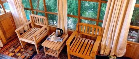 A cozy room with wooden furniture, a patterned rug, and large windows with curtains.