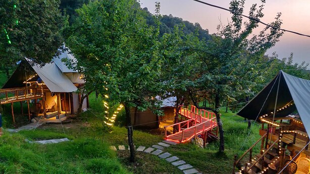 A campsite with tents, a wooden staircase, and string lights. - Camp Oak View (Baijnath)