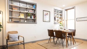 A dining area with a table, chairs, and a bookshelf. - Chic Brownstone in Historic Troy w/Furnished Deck (Troy)
